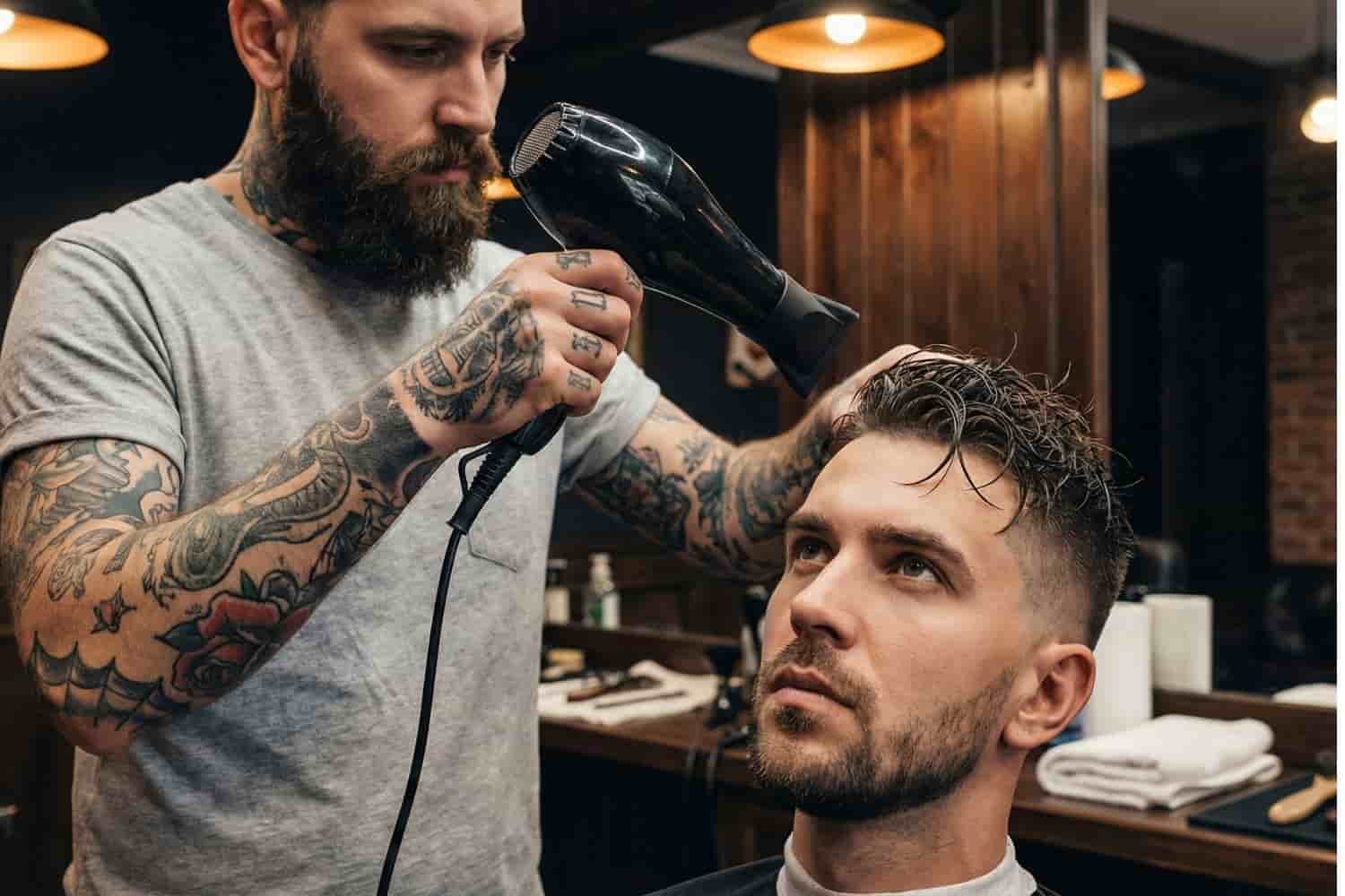 Barbero terminando un corte de cabello moderno con técnica de secado y peinado profesional en Ecatepec de Morelos.